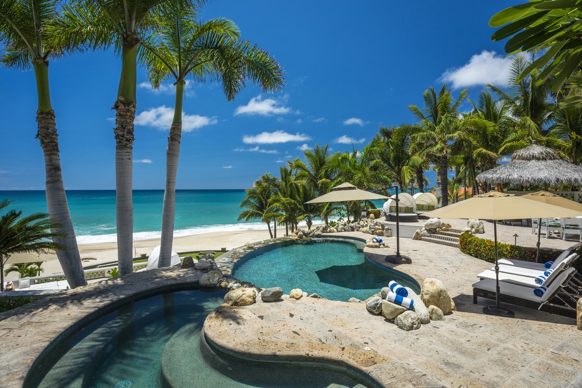 Beachfront luxury estate with palm trees and swimming pools in Palmilla, Los Cabos.